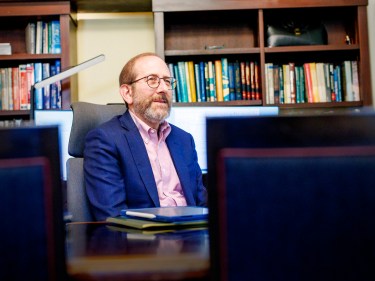 Alan Garber sitting at his desk in front of a bookshelf.